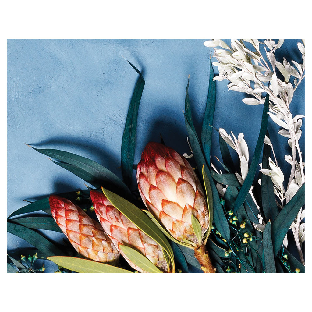PROTEA, EUCALYPTUS AND WHITE FOLIAGE ON BLUE PLACEMAT