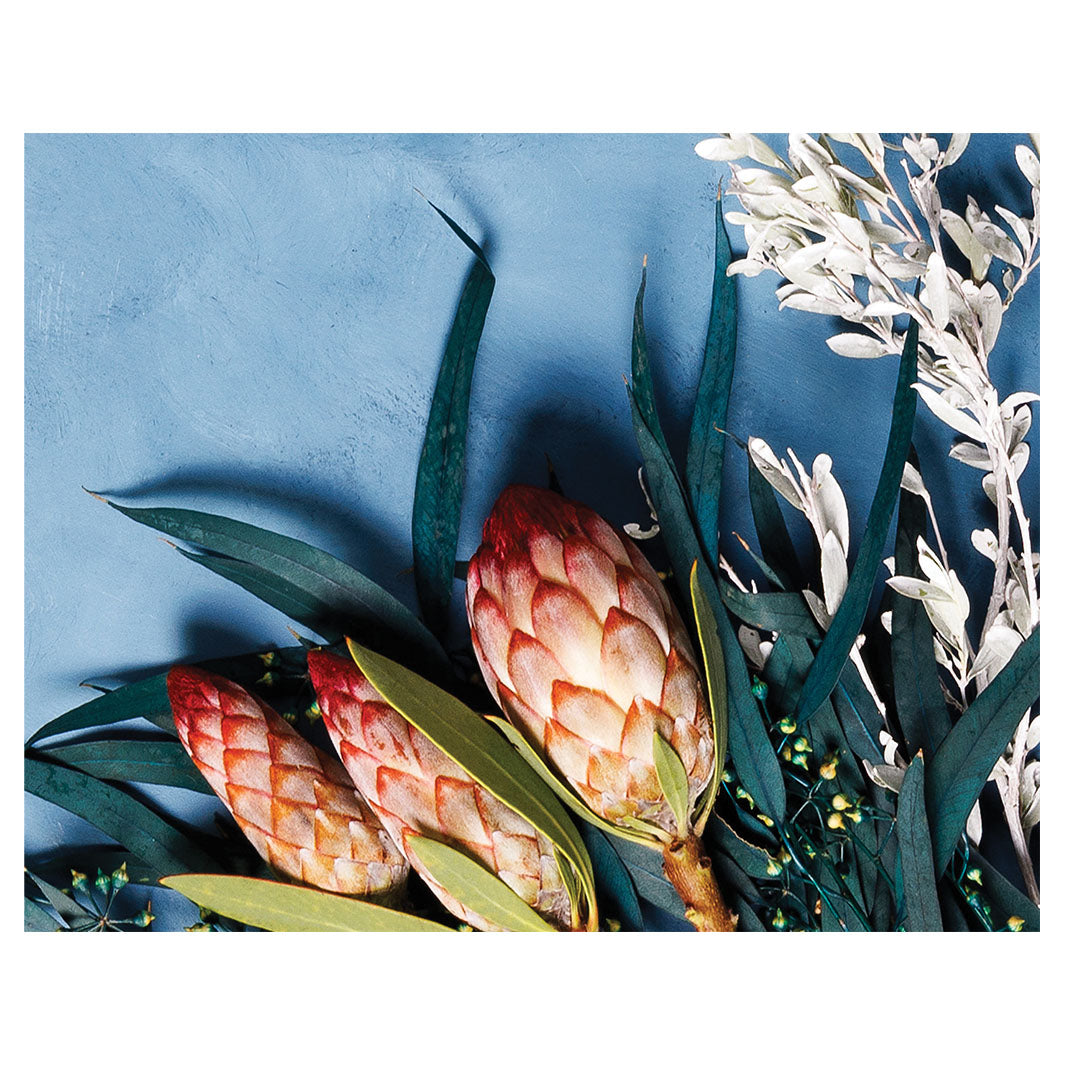 PROTEA, EUCALYPTUS AND WHITE FOLIAGE ON BLUE PLACEMAT