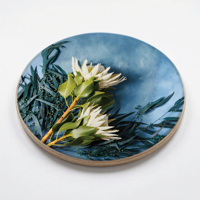 WHITE PROTEAS AND EUCALYPTUS ON BLUE CHEESEBOARD
