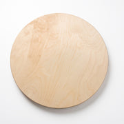 A round, light-colored wooden board with visible natural grain patterns, photographed from directly above on a clean white background.