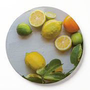 A round wooden serving board featuring a yellow-and-orange citrus-on-white print, displayed on a clean white background.