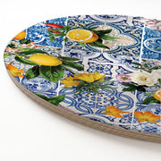 A round wooden serving board featuring a blue Lisbon tile with a lemons-and-flowers print, shown on a clean white background.