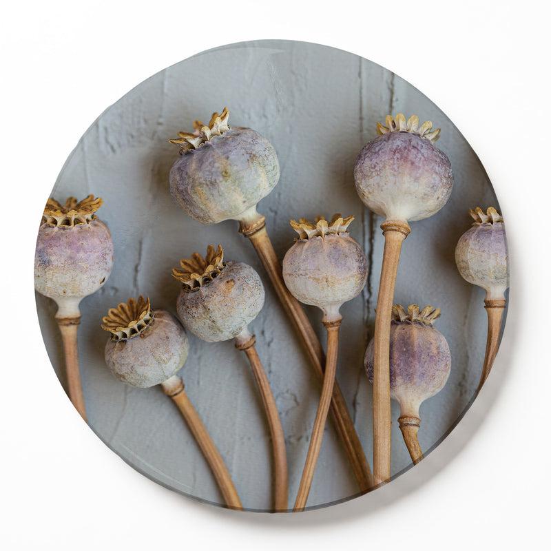 A round wooden serving board featuring a purple giant poppy seed print, shown on a white surface.