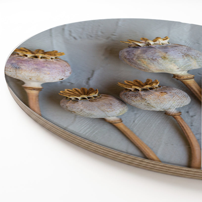 A round wooden serving board featuring a purple giant poppy seed print, shown on a clean white surface.