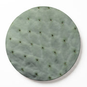 A round wooden serving board featuring a green prickly pear leaf print, photographed from directly above on a white background.