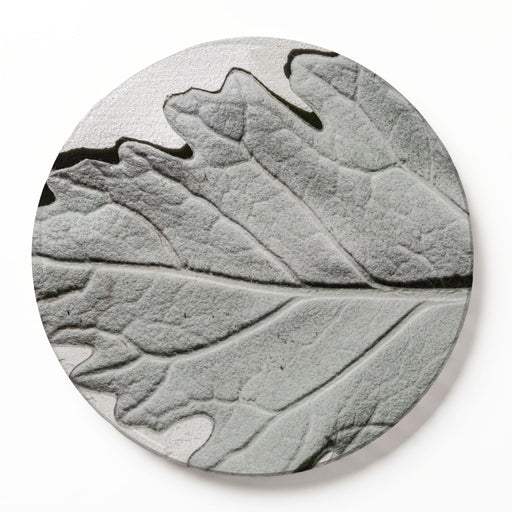 A round wooden serving board featuring a detailed, monochrome grey leaf print with black veins, set against a clean white background.