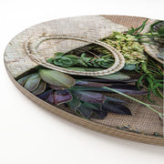 A round wooden serving board featuring a printed botanical and woven-texture design with succulents, burlap, and a straw basket motif, photographed on a clean white background.