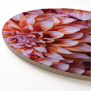 A close-up of a round wooden serving platter featuring a detailed photographic print of a pink-and-orange dahlia, set against a clean white background.