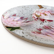 A round printed serving platter featuring a printed photographic design of pink protea flowers on a speckled light grey surface, shown on a clean white background.
