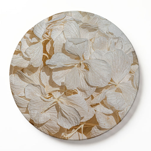 A round printed serving board featuring a close-up floral pattern of dried, bleached cream hydrangeas with beige and tan shadows, set against a clean white background.