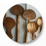 A round wooden serving board featuring a brown wooden spoons print, photographed on a white background.